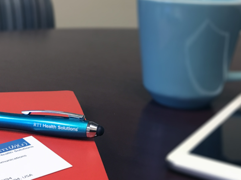 Folder and pen next to coffee and tablet