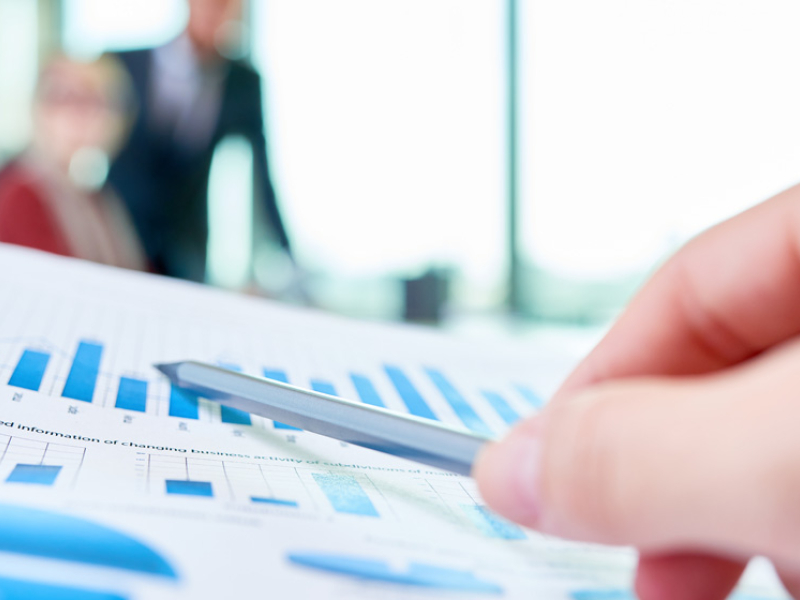 hand with pen pointing at graphs