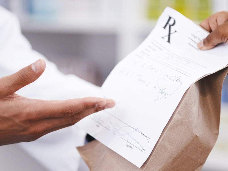 close-up of pharmacist hands giving prescription in a brown bag to patient